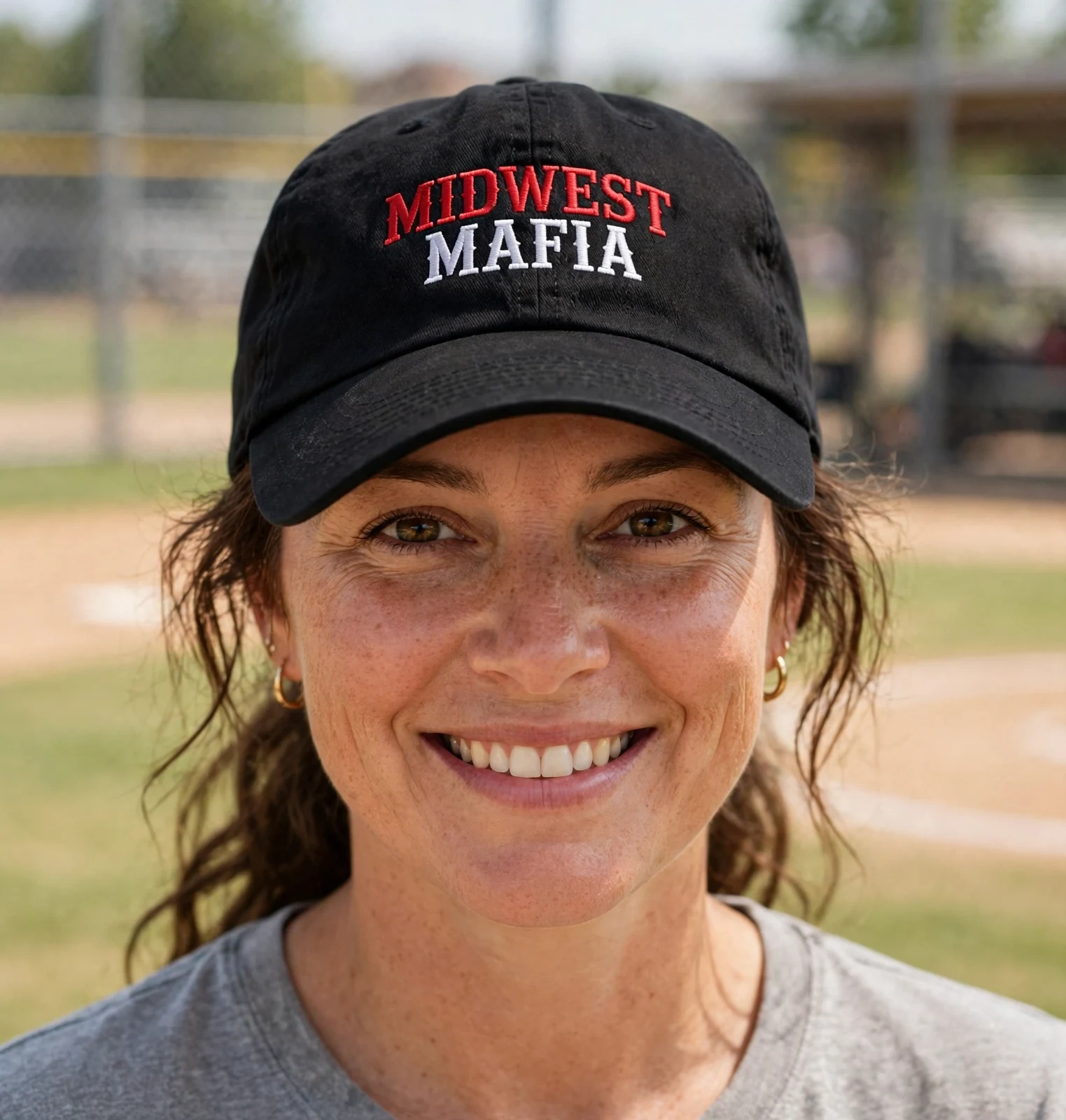 Adult softball fan wearing the black Midwest Mafia dad hat at the ballfield
